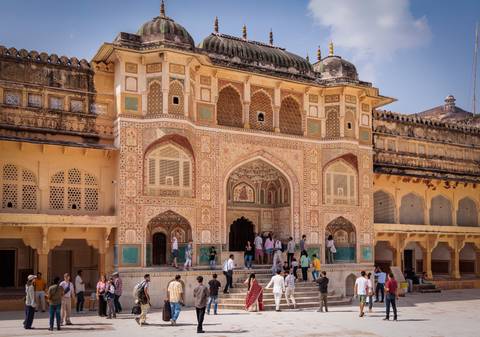Colorfully adorned entrance of Amber Fort with people moving through.