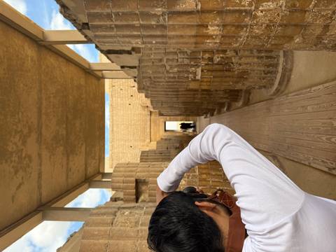       Person with camera photographing ancient stone columns.
  