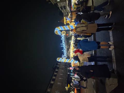 Christmas market entrance at night with a crowd in Strasbourg.