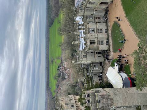       Aerial view of a castle with green fields and small village in the background.
  