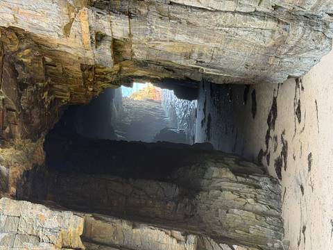       Rocky cave mouth leading to a bright opening.
  