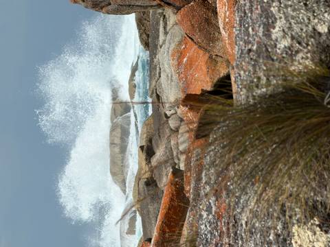 Waves crashing against large sea rocks with dramatic lighting.