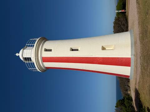       Lighthouse with red and white stripes under clear blue skies.
  