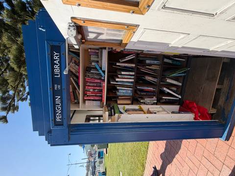       Library inside a small blue booth near the coast.
  