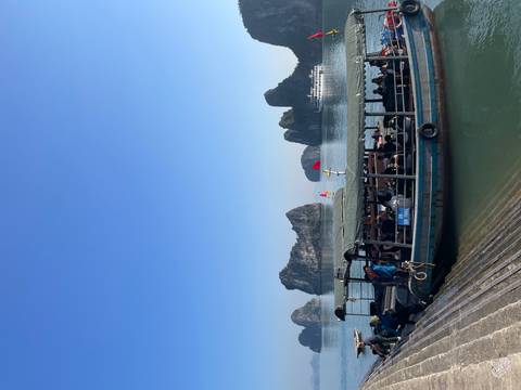 Tour boat with tourists looking out at karst formations.
