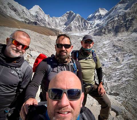       Group of trekkers smiling with mountains in the background.
  