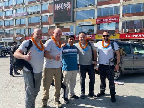       Group of friends standing in front of shops, smiling.
  