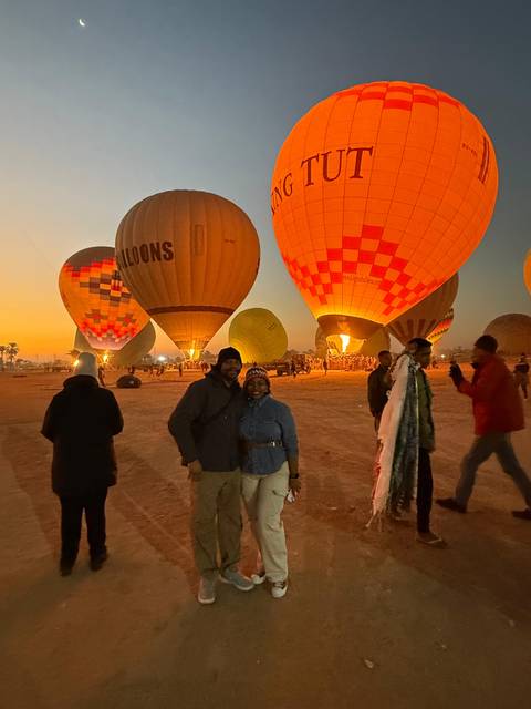 Hot air balloons at sunrise with people.