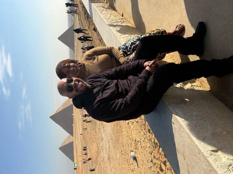 Couple sitting with pyramids in the background.