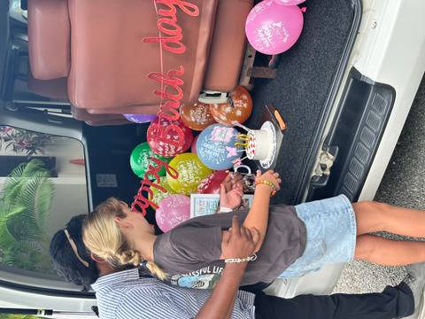 Child preparing to cut a cake among balloons.