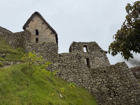 Stone structures and grassy areas at Machu Picchu with cloudy background.
