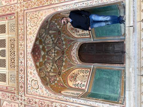 Ornate entrance of an Indian palace with a person posing.