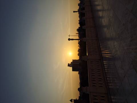       Sunset over a cityscape with a railing in the foreground.
  