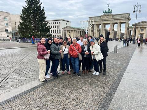       Group photo in front of the Brandenburg Gate with a Christmas tree nearby.
  