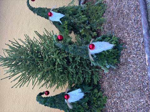       Decorative gnome-like figures made of tree branches with red ornaments.
  