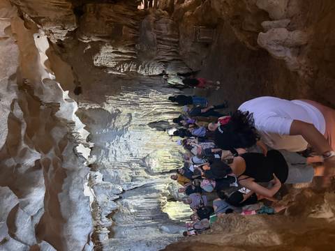 Group of people exploring a cave with stalactites and rock formations.