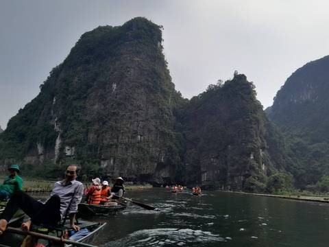 Tourists boating past limestone cliffs in a bay.