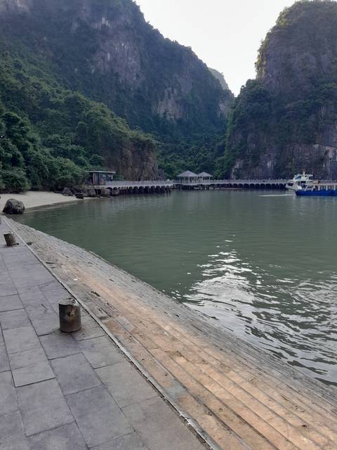 Wooden pier extending into a bay with hills.