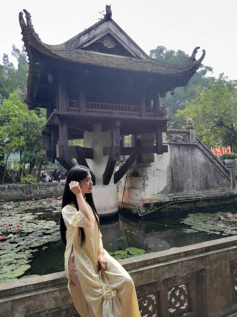 People outside a historic pagoda over a pond.
