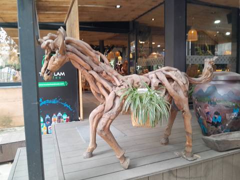 Wooden sculpture resembling an animal outside a cafe.