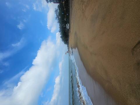       A sandy beach with a clear blue sky and ocean waves.
  