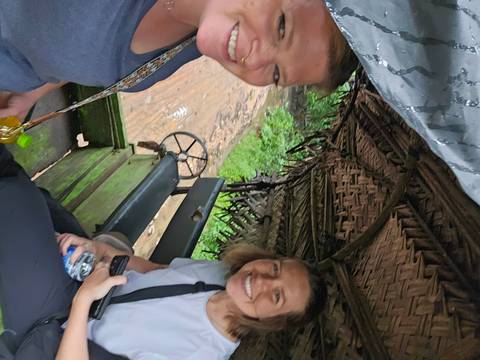       People sitting in a traditional cart with a woven roof.
  