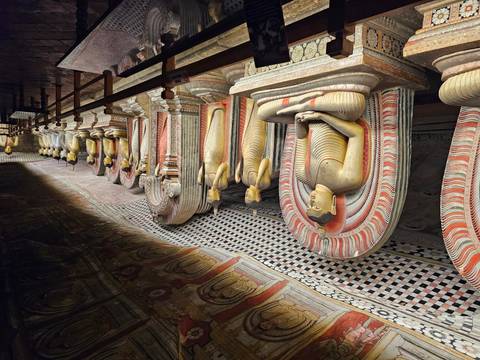 Rows of Buddha statues in a darkly lit cave temple.