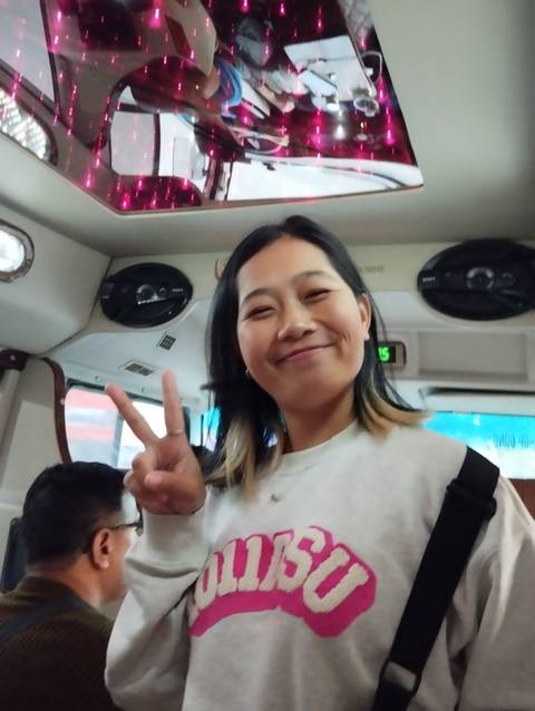       Smiling person making a peace sign inside a vehicle.
  