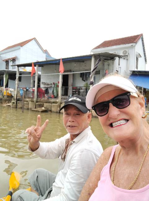       A woman smiling and giving a peace sign on a boat.
  