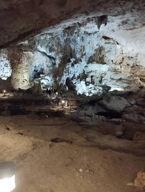       People exploring a cave with lit pathways.
  