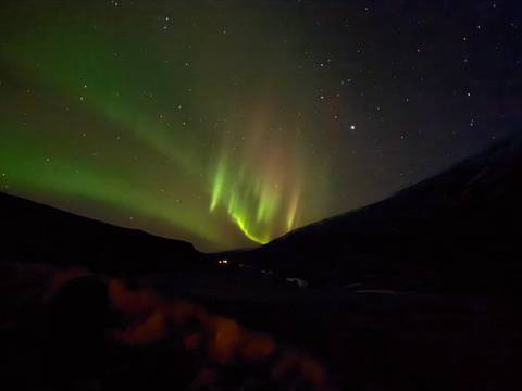 Aurora borealis in the night sky over a valley.