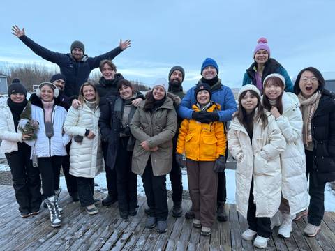 Large group of people smiling in winter clothing.
