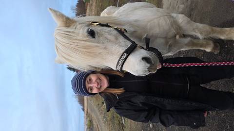       Smiling person with a white horse.
  