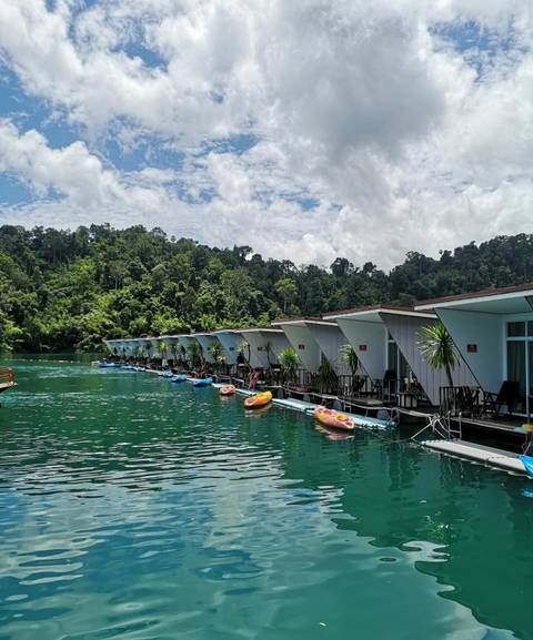 Row of floating resort accommodations on a green lake.