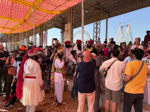 Crowd gathered at a cultural event with performers in traditional dress.