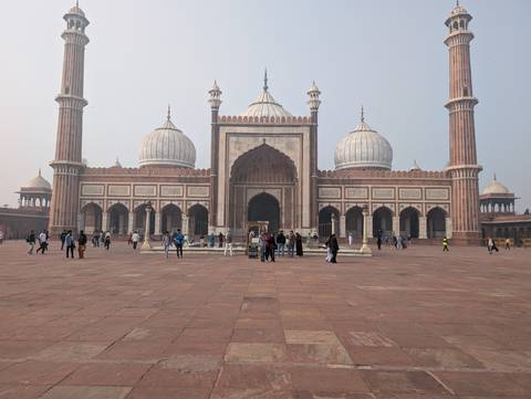 People visiting a large mosque with distinctive domes and minarets.