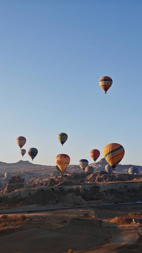 Hot air balloons rising over a rocky landscape.