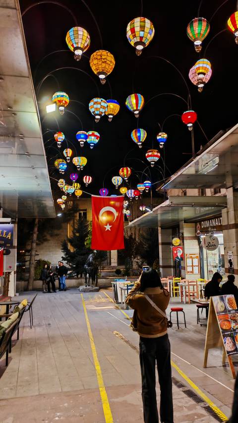 A Turkish flag with colorful lanterns at night.