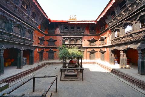A historic courtyard with intricate wood carvings and a traditional stone well in the center.