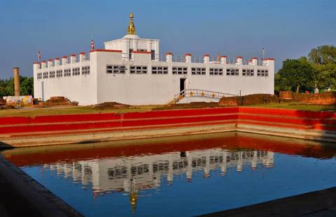 A historic white-washed temple with its reflection in a pond, likely a significant religious site.