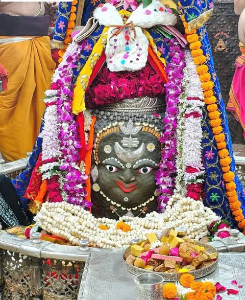 Decorated statue with colorful floral garlands.