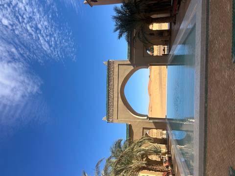       A pool with an archway and sand dunes in the background.
  