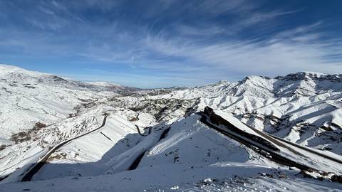       Aerial view of snow-covered winding roads in the mountains.
  