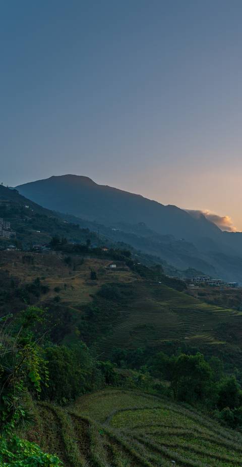       Mountain landscape during sunset with silhouetted slopes.
  