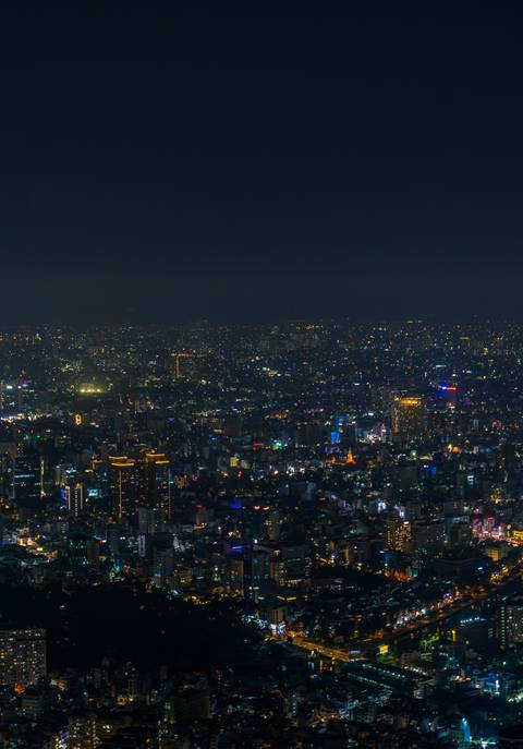       Expansive view of a city at night with illuminated buildings.
  