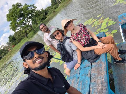 Four people taking a selfie on a boat in a serene lake.
