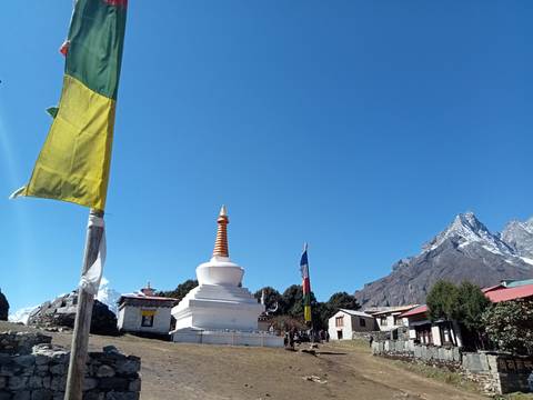 Stupa with snow-capped mountains under clear blue sky.