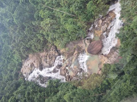       Waterfall flowing over rocks in lush forest.
  