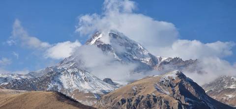 Snow-capped mountain with clouds above.