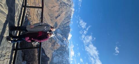 Two people standing on a balcony with mountain view.